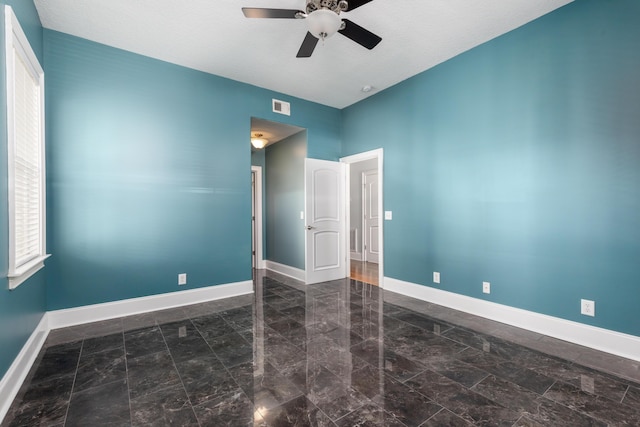 unfurnished room with ceiling fan and a textured ceiling