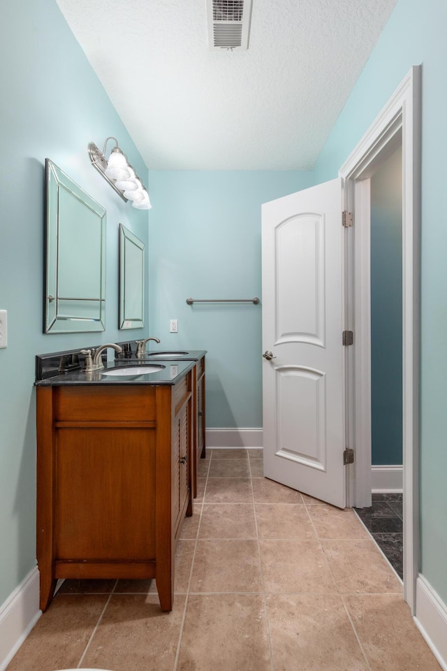 bathroom with tile patterned floors, vanity, and a textured ceiling