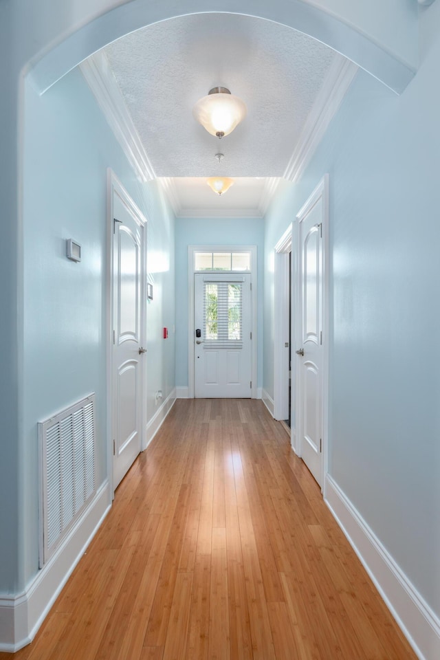 entryway with crown molding, a textured ceiling, and light wood-type flooring