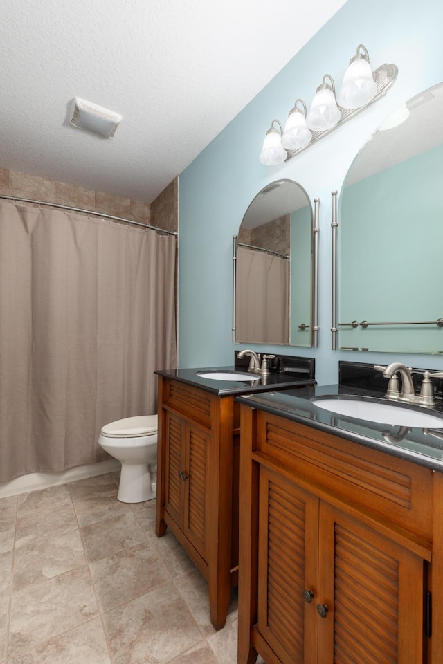 bathroom featuring a shower with curtain, vanity, a textured ceiling, and toilet