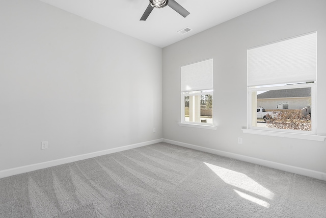 carpeted empty room with visible vents, a ceiling fan, and baseboards