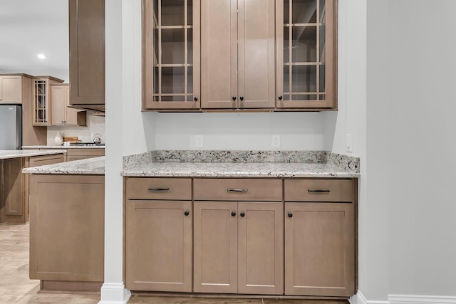 kitchen featuring light stone counters and stainless steel fridge