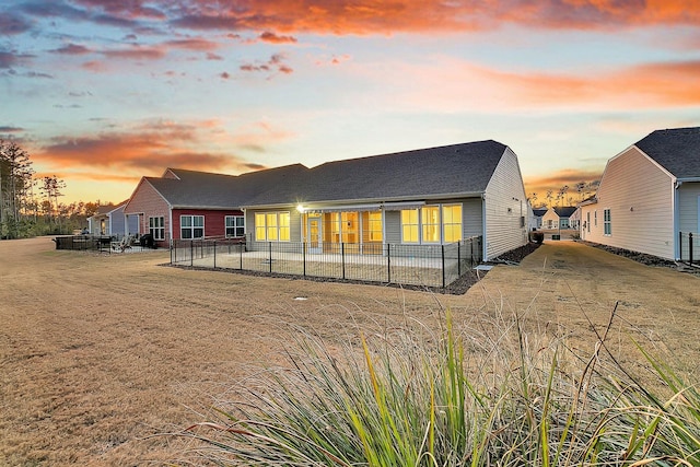 back house at dusk featuring a lawn