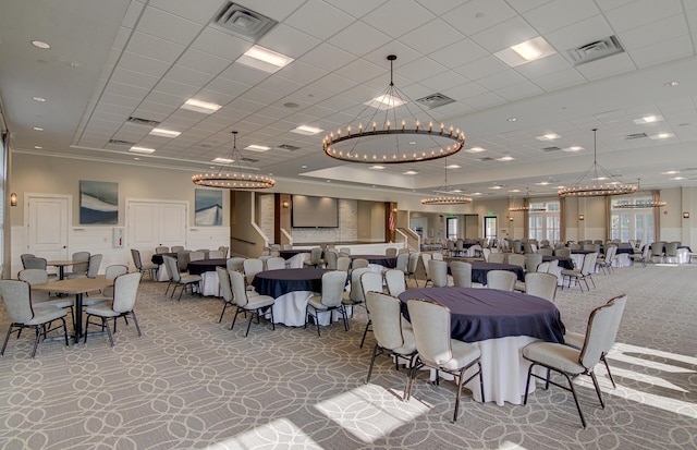 carpeted dining room with a drop ceiling and a notable chandelier