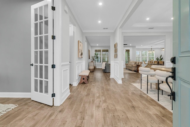 entryway with crown molding, a chandelier, and light wood-type flooring