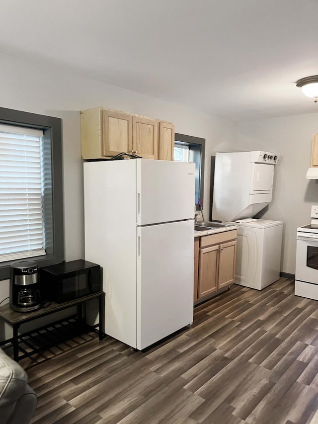 kitchen with white appliances, stacked washer and dryer, a wealth of natural light, and dark wood-type flooring