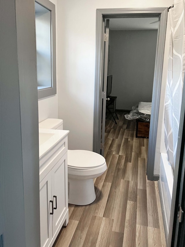 full bathroom with vanity, toilet, wood-type flooring, and shower / tub combo with curtain