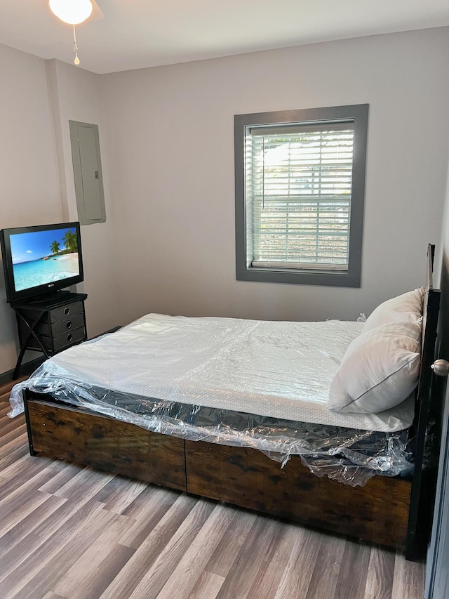 bedroom with electric panel, ceiling fan, and hardwood / wood-style flooring