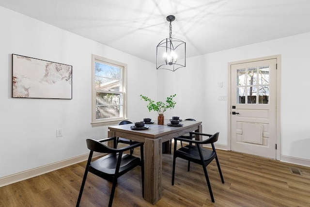 dining area featuring an inviting chandelier, baseboards, visible vents, and wood finished floors