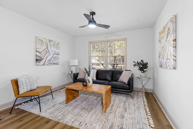 living area featuring wood finished floors, a ceiling fan, and baseboards