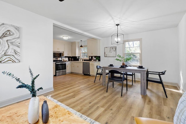 dining room with baseboards, a wealth of natural light, light wood-style flooring, and a notable chandelier