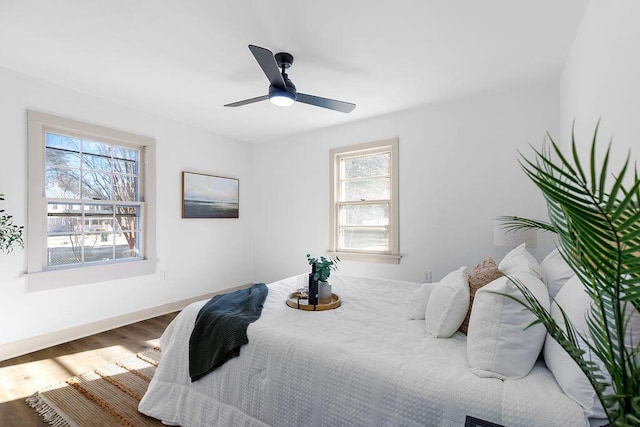 bedroom with wood finished floors, a ceiling fan, and baseboards