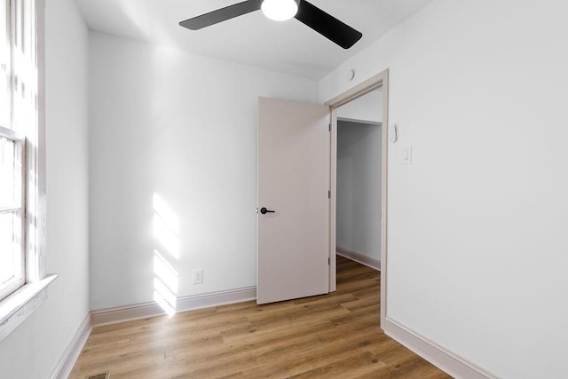 spare room with light wood-type flooring, baseboards, and a ceiling fan