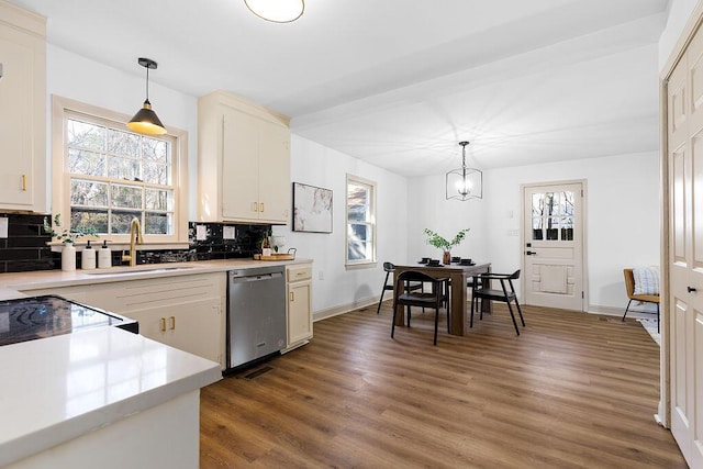 kitchen featuring tasteful backsplash, light countertops, dishwasher, and wood finished floors