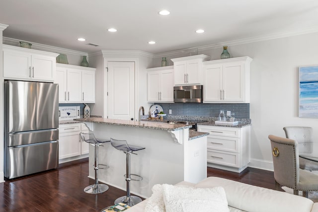 2087 Sterling Marsh Ln, Seabrook Island, SC 29455 - kitchen featuring appliances with stainless steel finishes, a breakfast bar, dark wood-type flooring, backsplash, and white cabinets