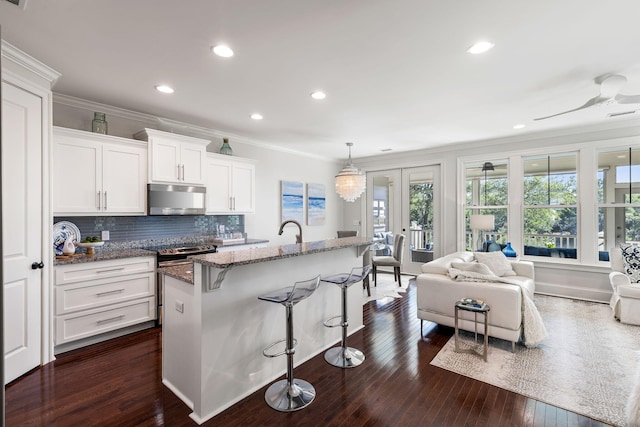 2087 Sterling Marsh Ln, Seabrook Island, SC 29455 - kitchen featuring electric range, ornamental molding, stone countertops, a kitchen bar, and white cabinetry