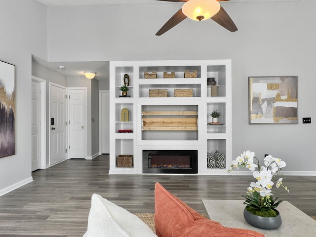 living room featuring ceiling fan, dark wood-type flooring, and built in shelves