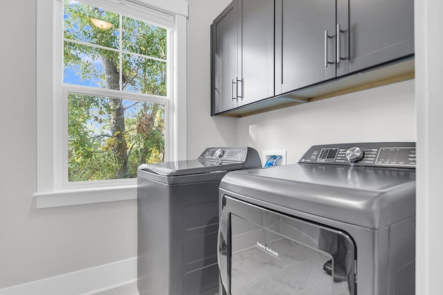 laundry area with cabinets, washing machine and dryer, and a wealth of natural light