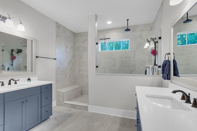 bathroom with a tile shower, vanity, and a healthy amount of sunlight