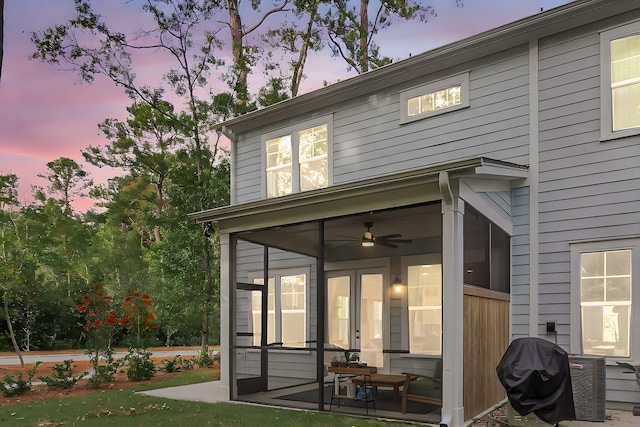 back house at dusk with a sunroom and ceiling fan