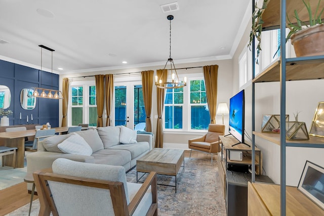 living room featuring hardwood / wood-style flooring, a notable chandelier, ornamental molding, and french doors