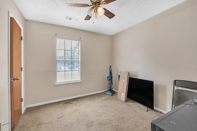 unfurnished bedroom featuring light carpet, a textured ceiling, and ceiling fan