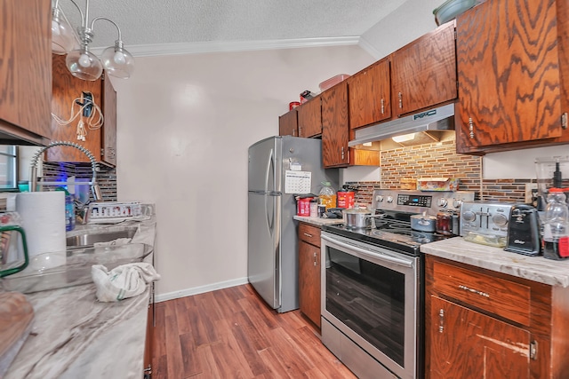 kitchen with a textured ceiling, wood-type flooring, crown molding, and stainless steel appliances