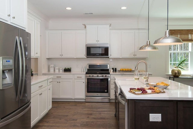 kitchen featuring pendant lighting, decorative backsplash, white cabinets, and appliances with stainless steel finishes