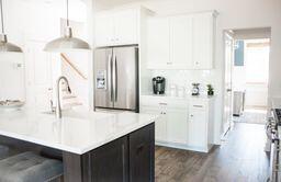 kitchen featuring stainless steel appliances, tasteful backsplash, white cabinets, a center island with sink, and dark hardwood / wood-style flooring