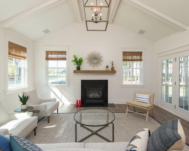 living room with hardwood / wood-style flooring, a healthy amount of sunlight, a chandelier, and lofted ceiling with beams