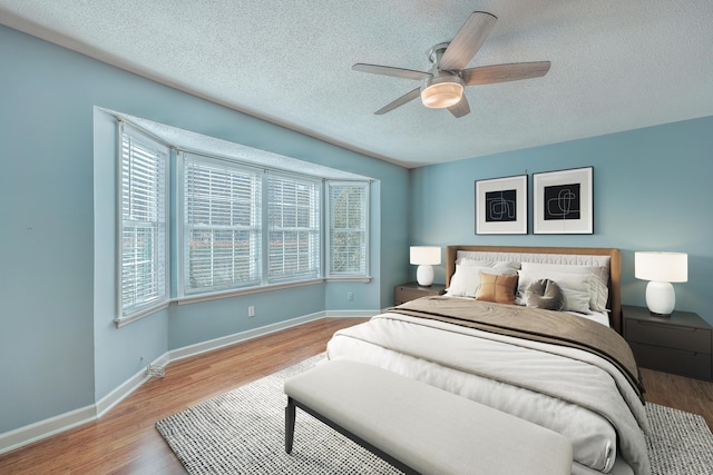 bedroom featuring a textured ceiling, ceiling fan, and light hardwood / wood-style flooring