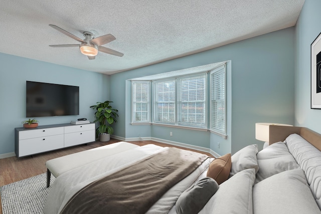 bedroom featuring ceiling fan, hardwood / wood-style floors, and a textured ceiling