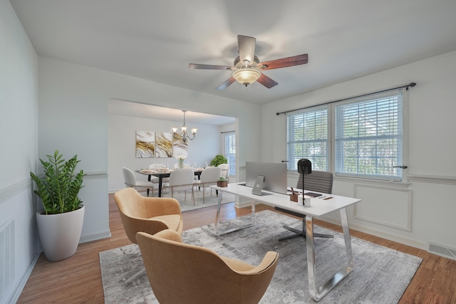 office featuring ceiling fan with notable chandelier and light hardwood / wood-style floors