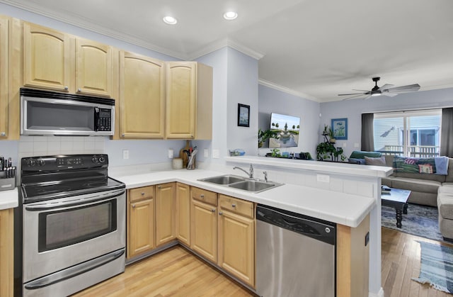 kitchen featuring stainless steel appliances, sink, light brown cabinetry, and kitchen peninsula