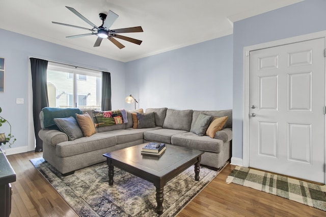 living room with wood-type flooring, ornamental molding, and ceiling fan