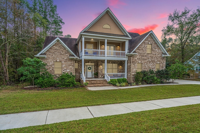 view of front of home with a lawn, a balcony, and a porch