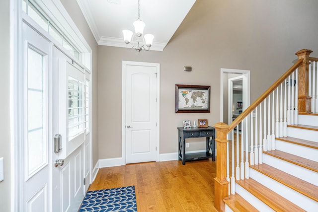 foyer entrance with crown molding, a chandelier, and light wood-type flooring