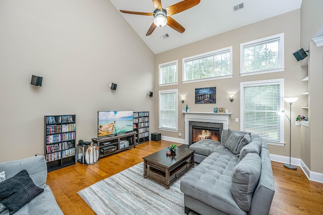 living room featuring ceiling fan, high vaulted ceiling, and light wood-type flooring