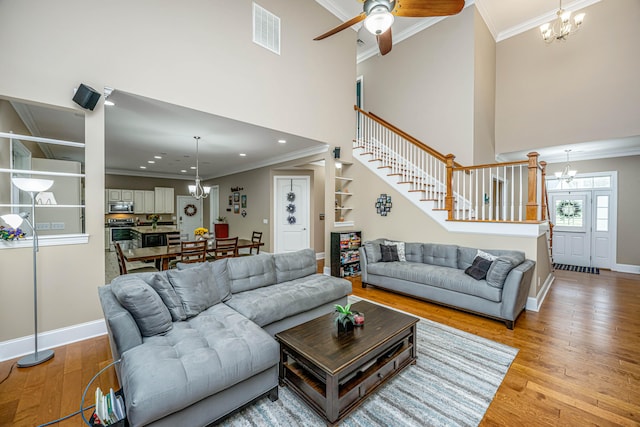 living room with ornamental molding, ceiling fan with notable chandelier, and light wood-type flooring