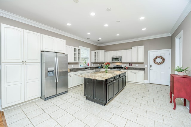 kitchen with white cabinets, appliances with stainless steel finishes, a center island, and crown molding