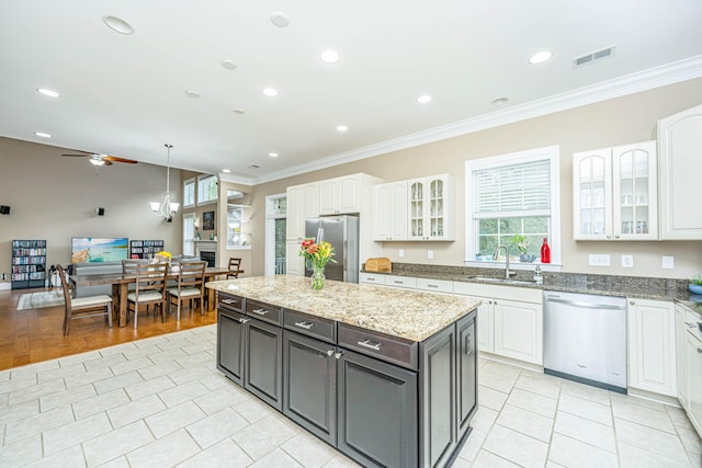 kitchen with white cabinets, crown molding, sink, appliances with stainless steel finishes, and decorative light fixtures