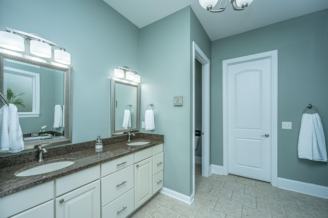 bathroom featuring tile patterned flooring, vanity, a chandelier, and toilet