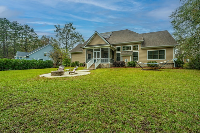 back of property featuring a lawn, a patio area, a sunroom, and a fire pit