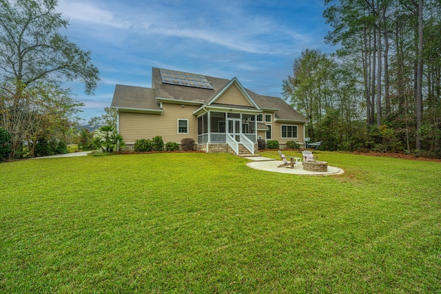 back of house with a sunroom, solar panels, and a lawn