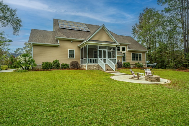 back of house featuring solar panels, a yard, a fire pit, and a sunroom