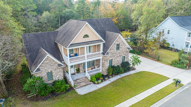 view of front of property featuring covered porch, a balcony, and a front yard