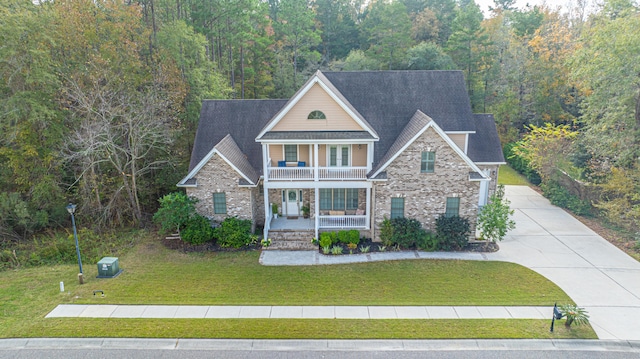 view of front of property featuring covered porch, a balcony, and a front lawn