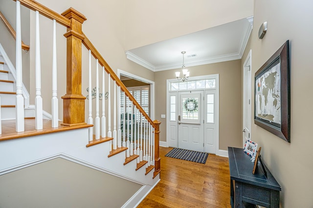 entryway featuring hardwood / wood-style floors, crown molding, and a chandelier