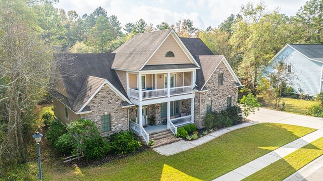 view of front of home featuring a balcony, covered porch, and a front yard