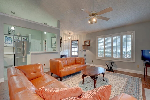 living room featuring wood-type flooring, lofted ceiling, ceiling fan, and a textured ceiling